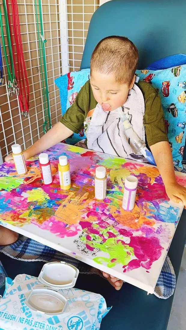 A child finger painting at a table during therapy